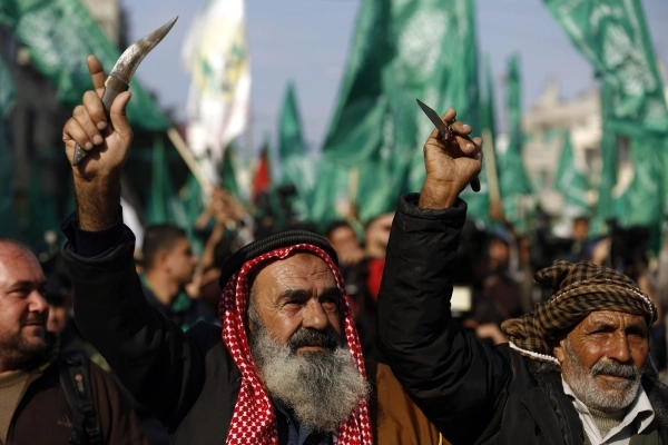فلسطينيون يحملون سكاكين وخناجر في احتفال حماس بالذكرى الـ28 للحركة بغزة (أ ف ب)
