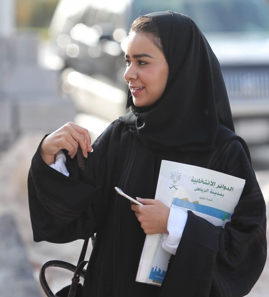 ناخبة تحمل كتيبا عن الانتخابات البلدية أمام أحد مراكز الاقتراع في الرياض (محمد مشهور)