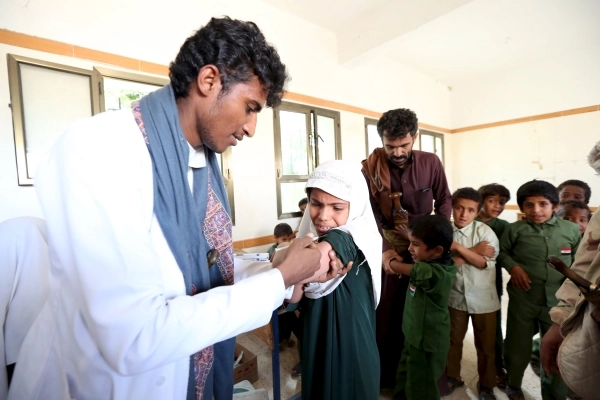 موظف بالصحة يطعم طلبة في مدرسة وسط محافظة مأرب (رويترز)