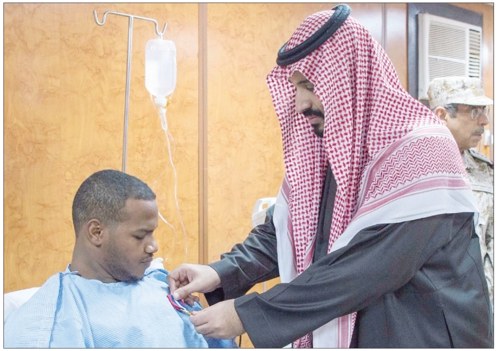 الأمير محمد بن سلمان يقلد جنديا نوطي الشرف والمعركة في جازان أمس (واس)