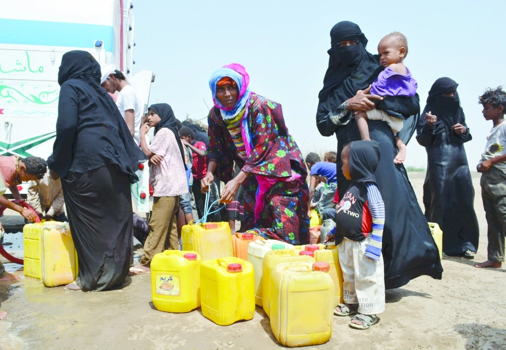 يمنيات ينتظرن الحصول على مياه للشرب قرب مخيم بالحديدة                                      (رويترز)