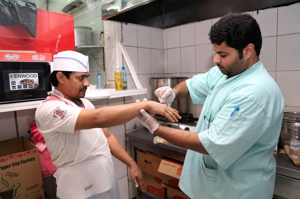 
    مراقبو الحملة لحظة الكشف عن الجراثيم على أيدي العمال بحي المسفلة (أحمد جابر)