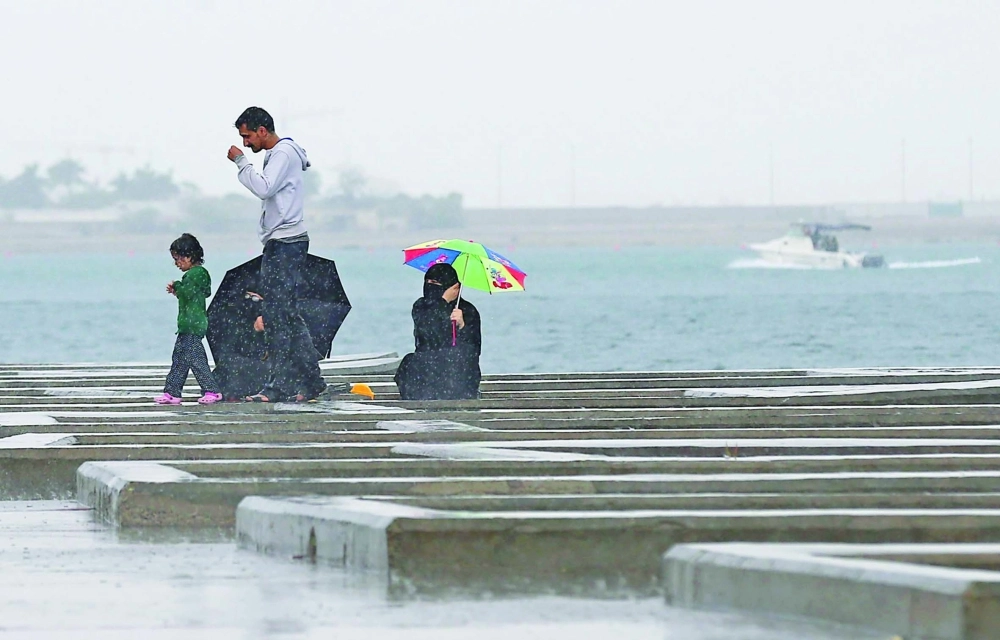 عائلة تجلس عند شاطئ البحر أثناء هطول الأمطار  (ثامر الفرج)