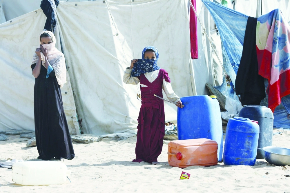 Girls stand outside a tent at a camp for internally displaced people in Yemen's central province of Marib
