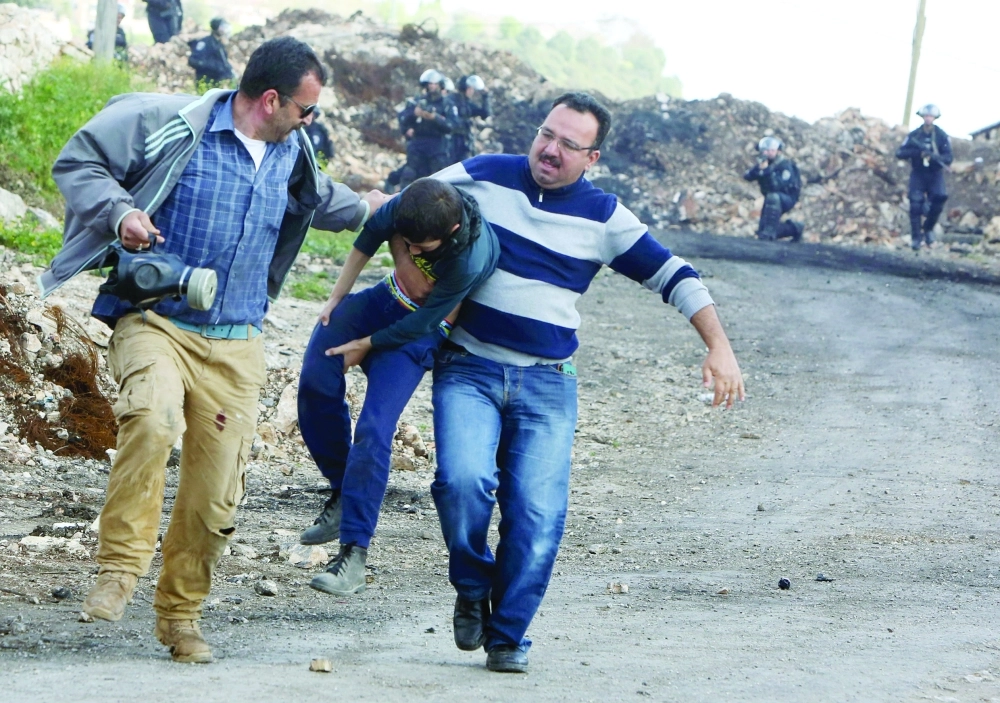 فلسطيني يحمل صبيا بعد اشتباكات مع الاحتلال قرب نابلس         (أ ف ب)