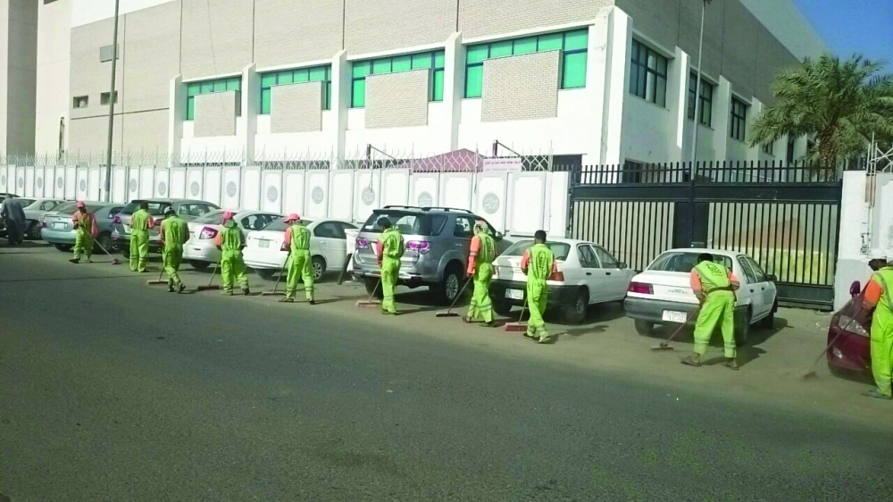 عمال الأمانة أثناء كنس أحد الشوارع يدويا      (مكة) 