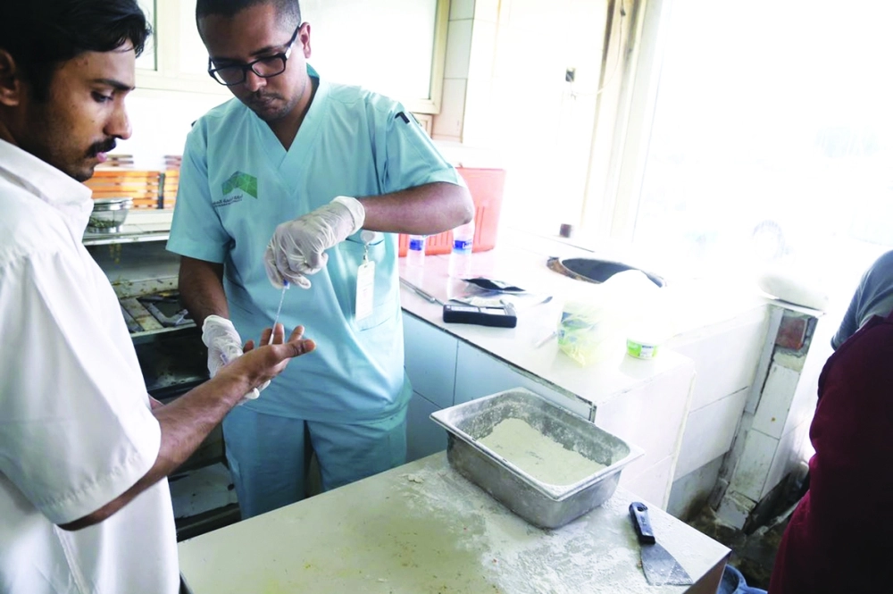 مراقب يفحص يدي أحد العمال خلال الحملة         (عبدالله الشنقيطي)