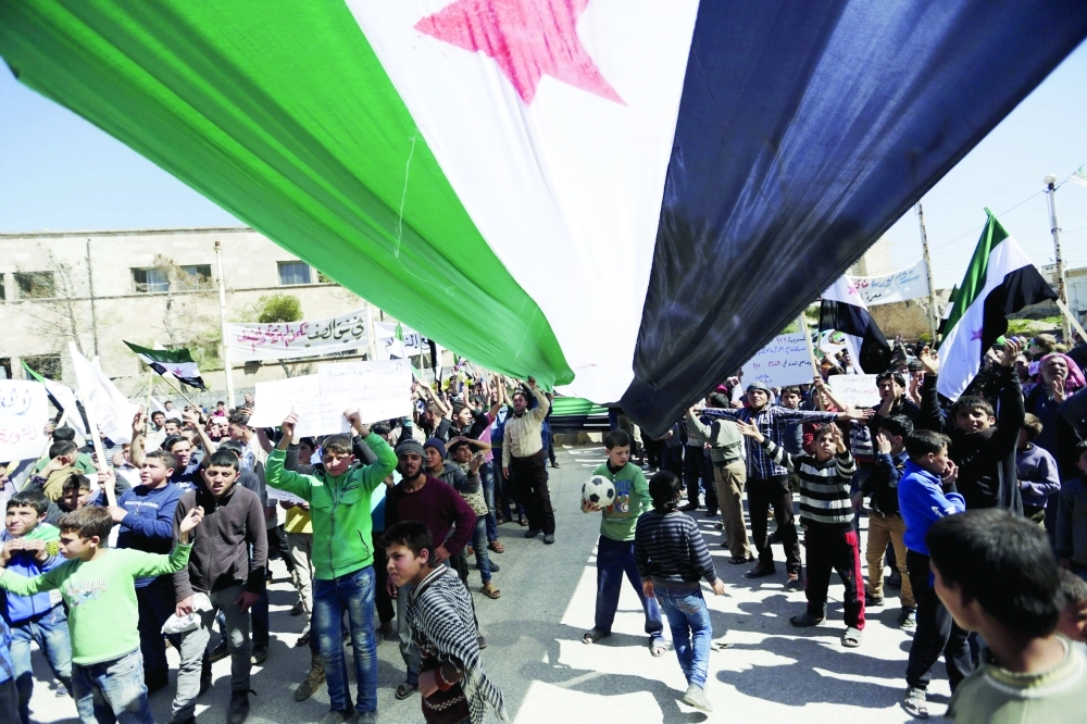 معارضون لنظام الأسد يرفعون علم الثورة في احتجاج ضد الحكومة في معرة النعمان بإدلب أمس          (رويترز)