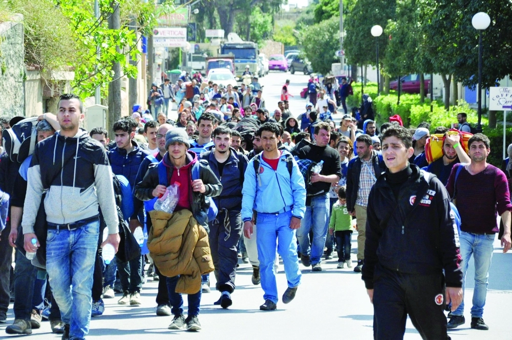 مهاجرون يسيرون في شارع بجزيرة شواس اليونانية                                           (إ ب أ)