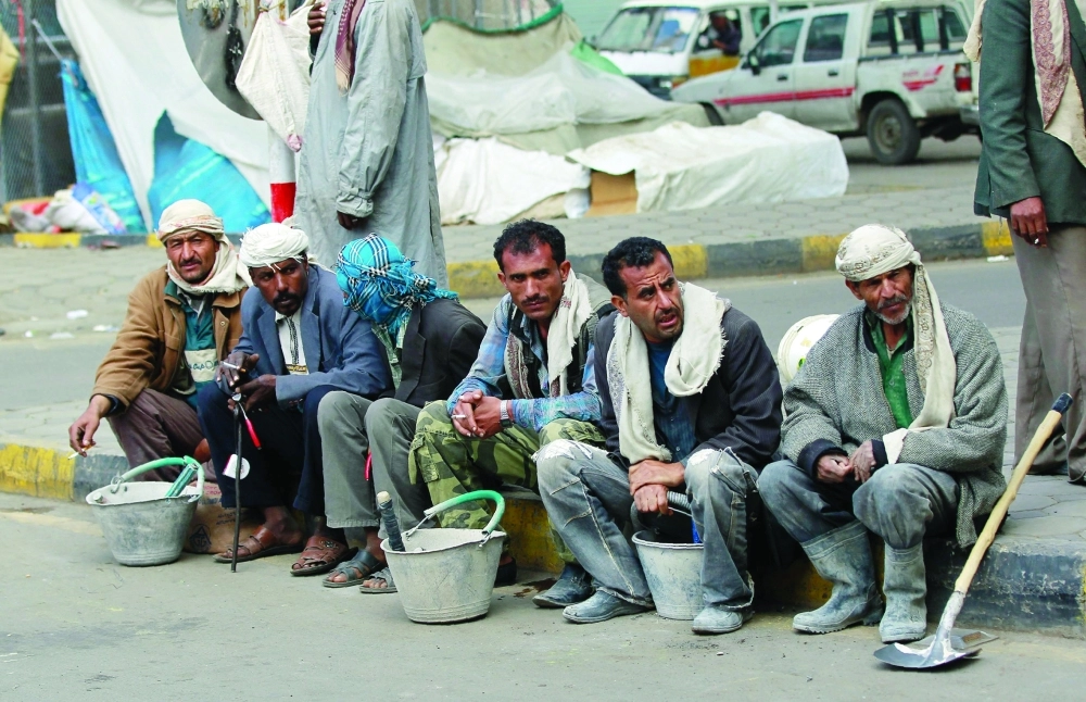 عمال ينتظرون أصحاب الأعمال على جانب طريق بصنعاء، التي تشهد تدهورا في المعيشة بفعل الانقلابيين             (أ ف ب)