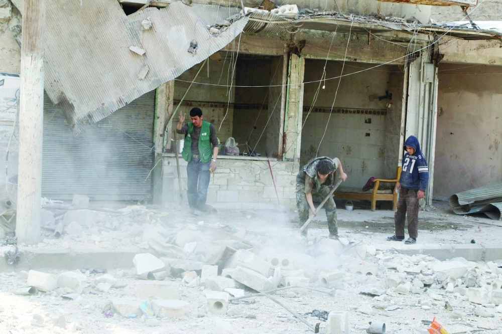 سوريون يزيلون أنقاض منزل قصفه النظام في حلب              (رويترز)