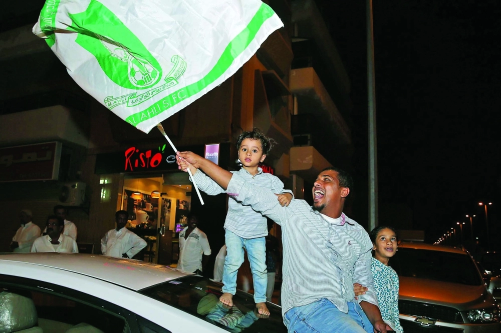 مشجع يحمل علم الأهلي برفقة طفله (ثامر الفرج)