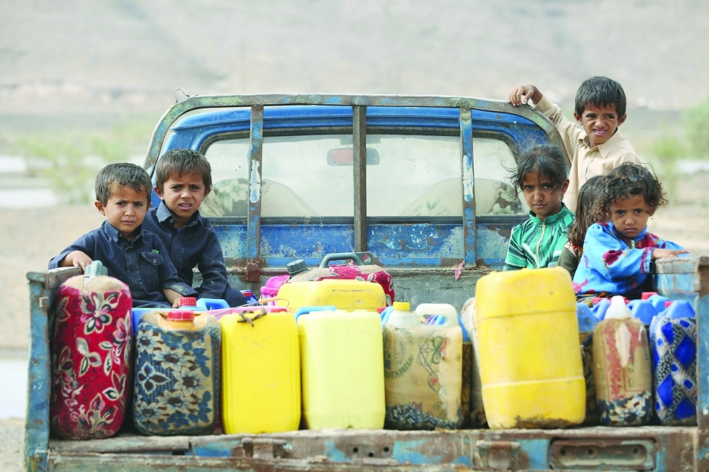 أطفال بجوار عبوات بلاستيكية فوق شاحنة في طريقهم للحصول على مياه للشرب في مأرب     (رويترز)