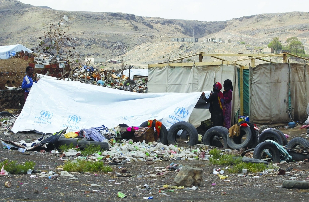 يمنيون ينصبون خيمة موقتة داخل معسكر للاجئين في منطقة عمران           (إ ب أ) 