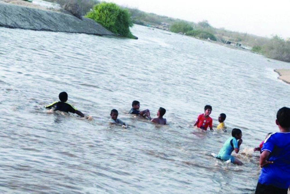 أطفال حلي يلهون في مياه السد بعد فتح بواباته أخيرا                          (مكة)