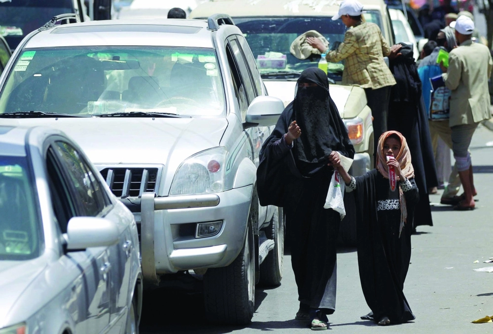 يمنية وابنتها تتسولان في ظل احتياج 80 % من الشعب جراء الانقلاب على الشرعية (أ ف ب)
