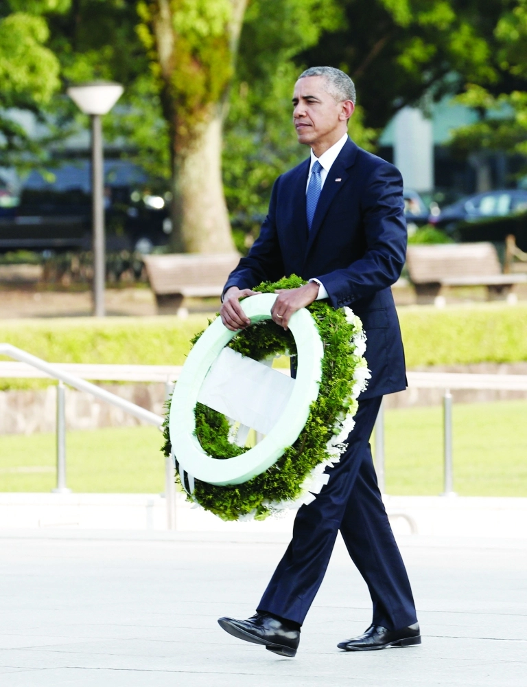 .. ويحمل إكليلا من الورد لوضعه على النصب التذكاري                    (رويترز)