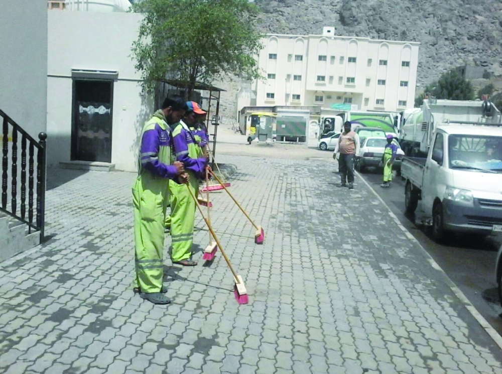 عدد من العمال خلال نظافة أحد الشوارع        (مكة)