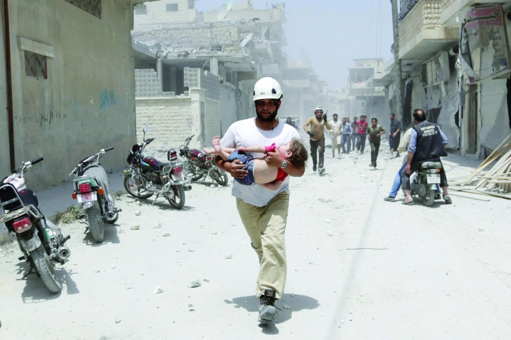 مسعف ينقل طفلة مصابة بعد غارة لطيران الأسد على معرة النعمان  (رويترز)