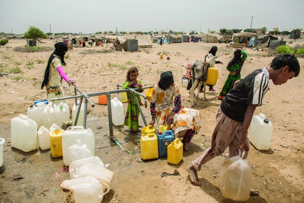أطفال يمنيون يملؤون عبوات بلاستيكية بالمياه قرب مخيم المانجورة بمحافظة حجة                (إ ب أ)