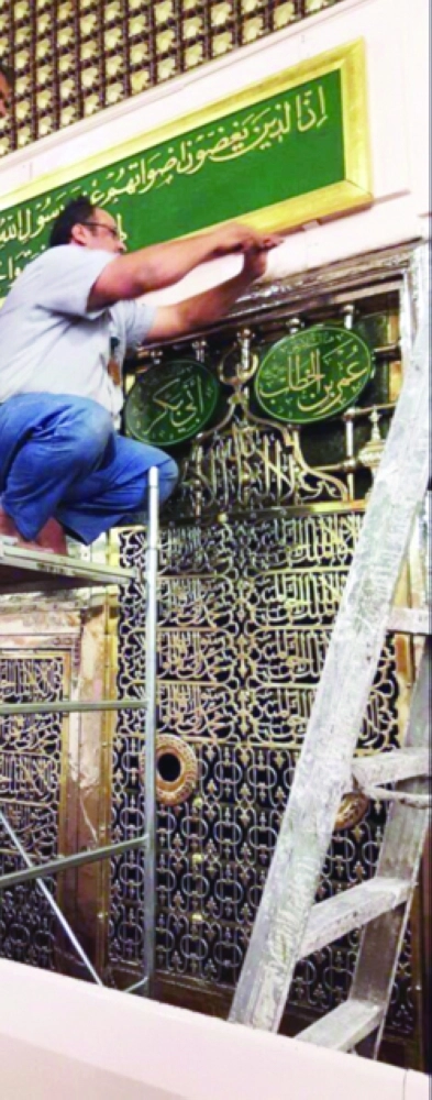 عامل لدى إزالته اللوحة القرآنية القديمة             (مكة)