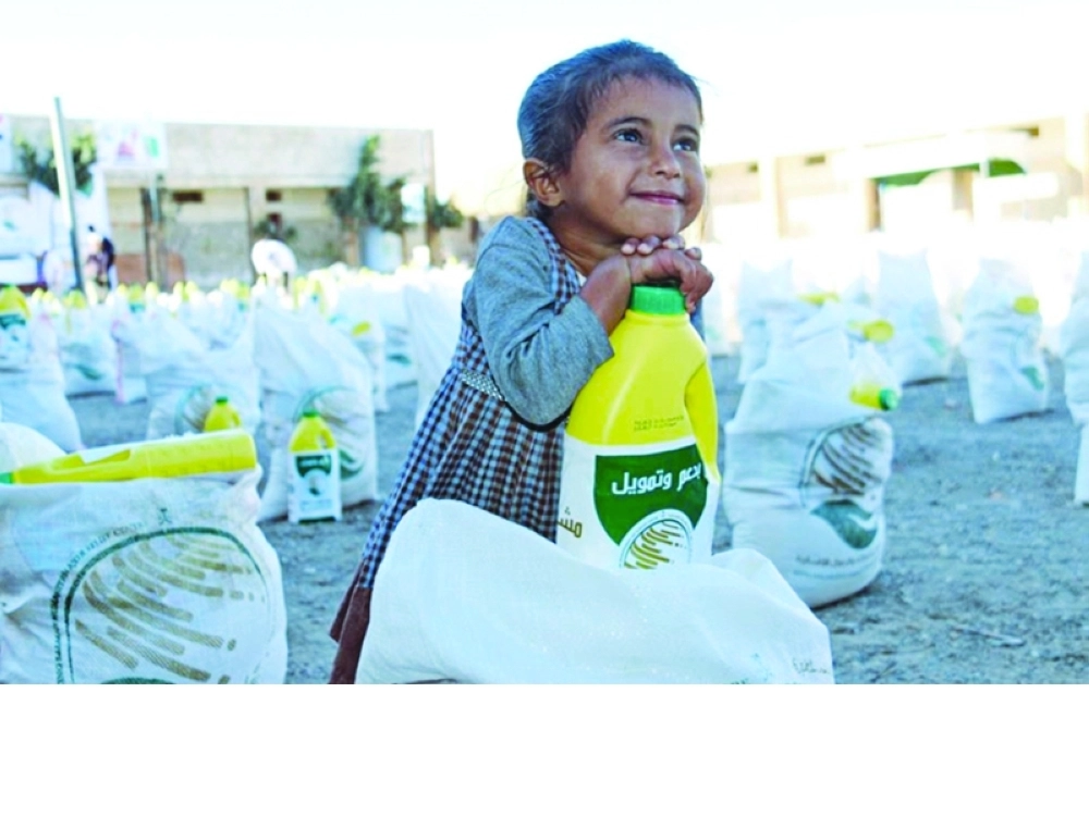 طفلة يمنية تقف بجوار سلال غذائية يوزعها مركز الملك سلمان للإغاثة                  (واس)