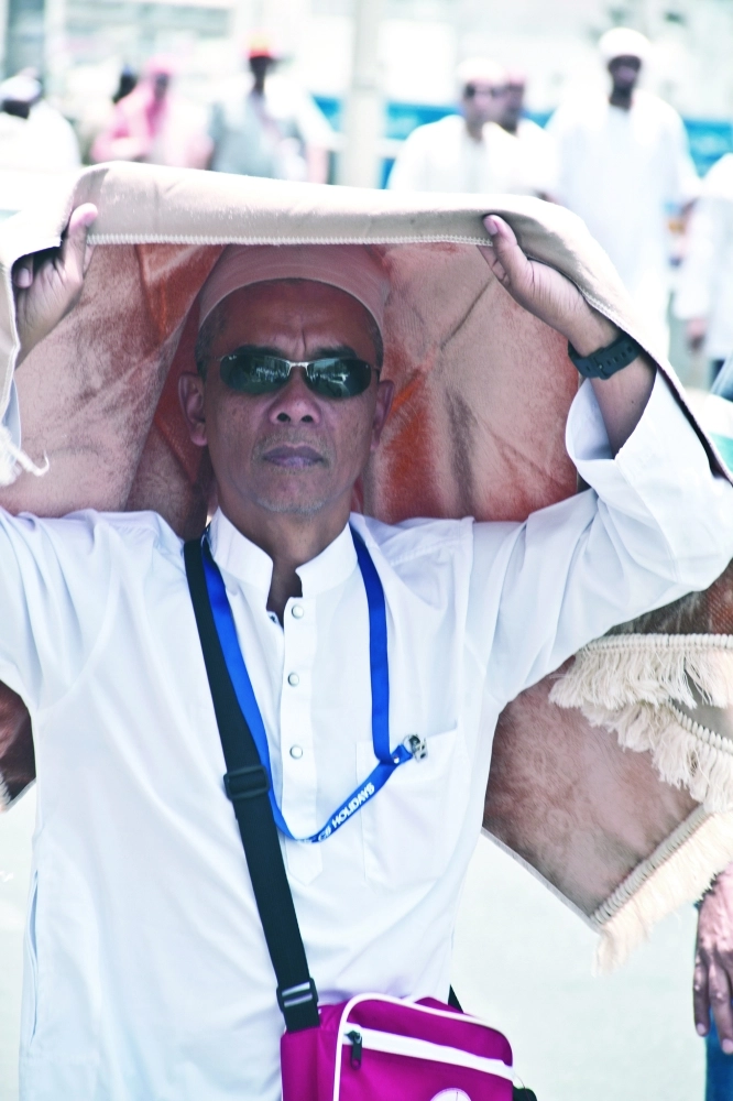 أحد المصلين يستظل بسجادة من حرارة الشمس    (أنس الحارثي)