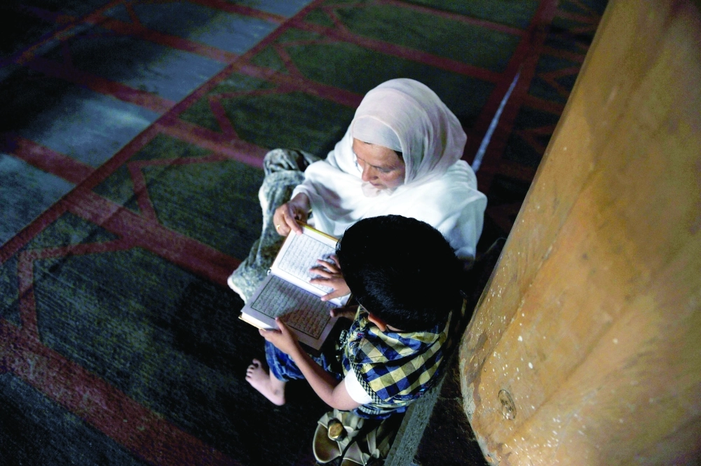 كشميرية تعلم ابنها قراءة القرآن بمسجد في سريناجار 