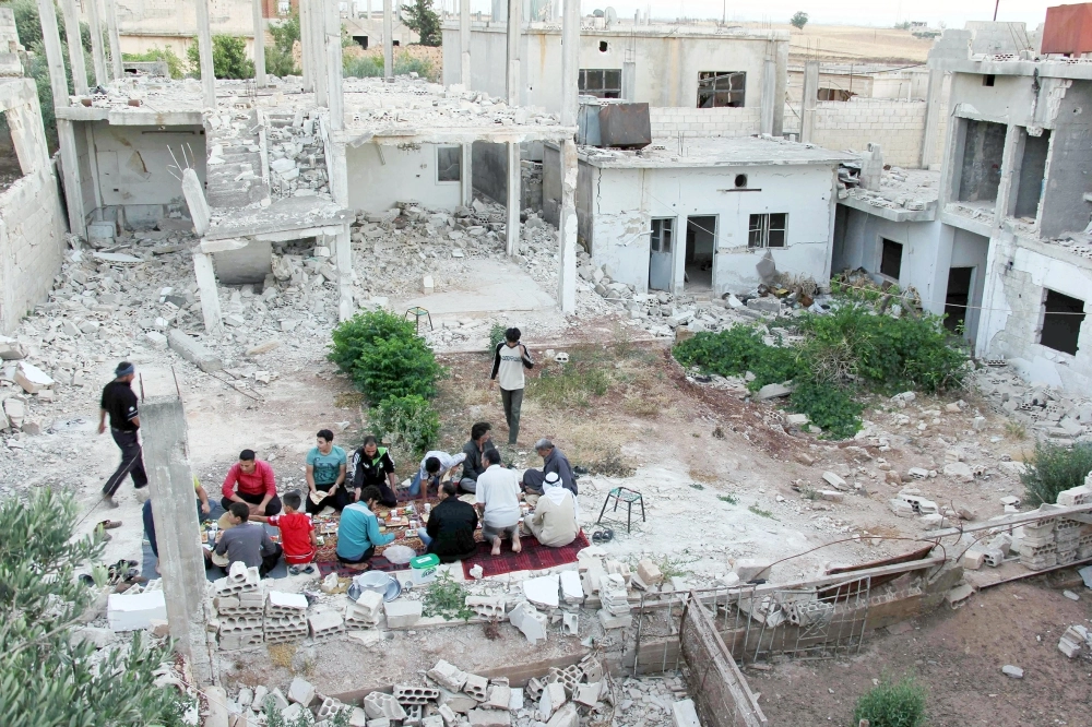 سوريون يستعدون لإفطار رمضان وسط منازل مدمرة قرب حمص          (أ ف ب)