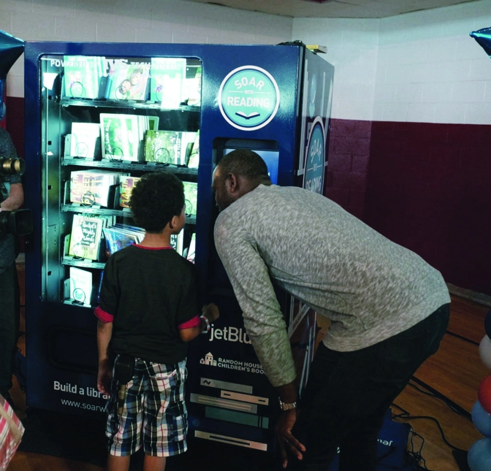 جستن ابتون يتحدث مع أحد الأطفال أمام آلة البيع                 (Daily Detroit)