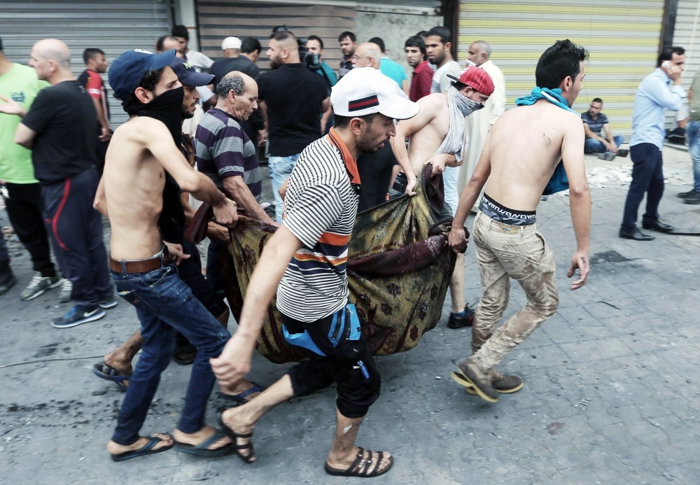 عراقيون يحملون جثمان قتيل في تفجير الكرادة أمس       (أ ف ب)