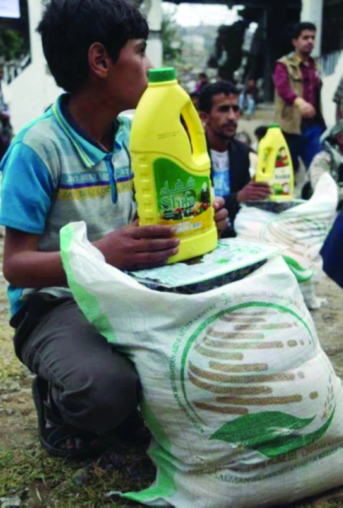 صبي يمني يحمل مساعدات غذائية سعودية في تعز