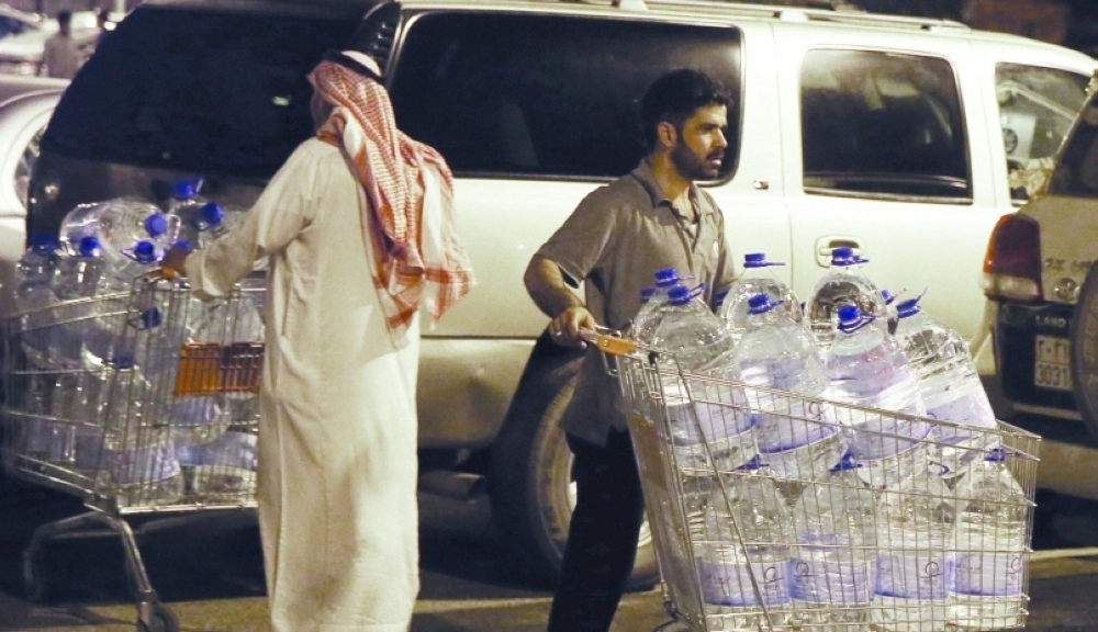 ينقلان عبوات زمزم إلى سيارتيهما أمام مشروع السقيا (ياسر بخش)