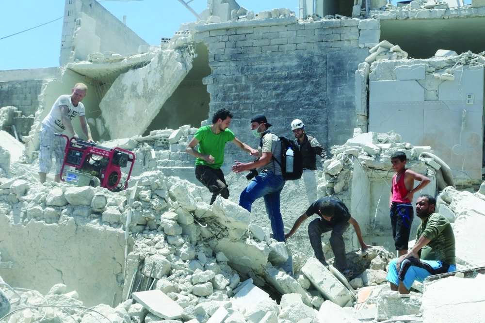 سوريون يسيرون فوق حطام المنازل إثر غارة للنظام بحلب القديمة  (رويترز)