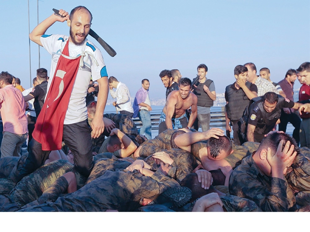 أنصار إردوغان يضربون جنودا شاركوا في الانقلاب، بعد اعتقالهم قرب جسر البوسفور أمس (رويترز)