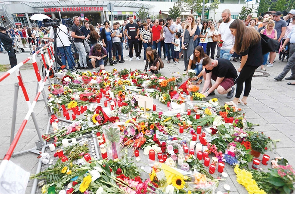 ألمان يضعون الزهور أمام المركز التجاري الذي شهد الاعتداء (رويترز)


