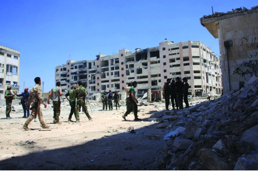 دمار المباني بمنطقة ليرامون جنوب غرب حلب، فيما يتفقد جنود النظام المنطقة (أ ف ب) 