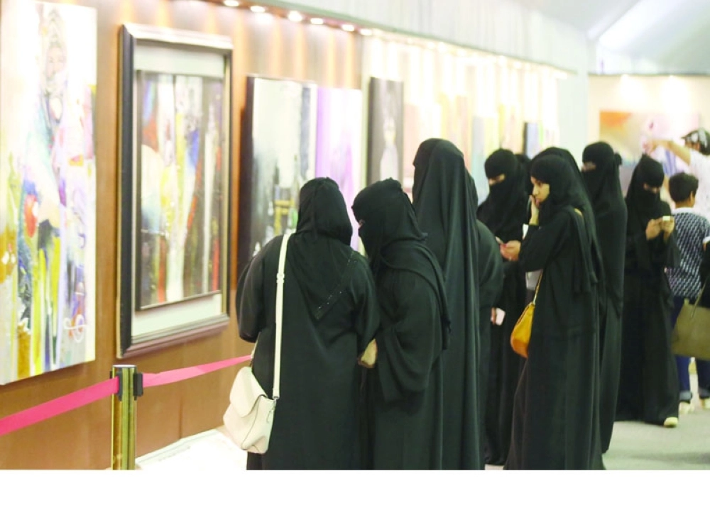 زائرات يتأملن لوحات داخل المعرض