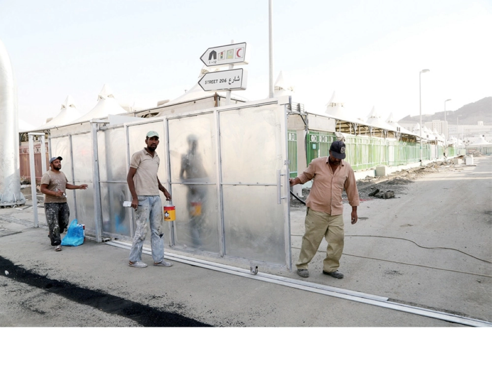 عمال يركبون بوابة للتحكم بإدارة الحشود في طريق 206 بمنى أمس (أحمد جابر)
