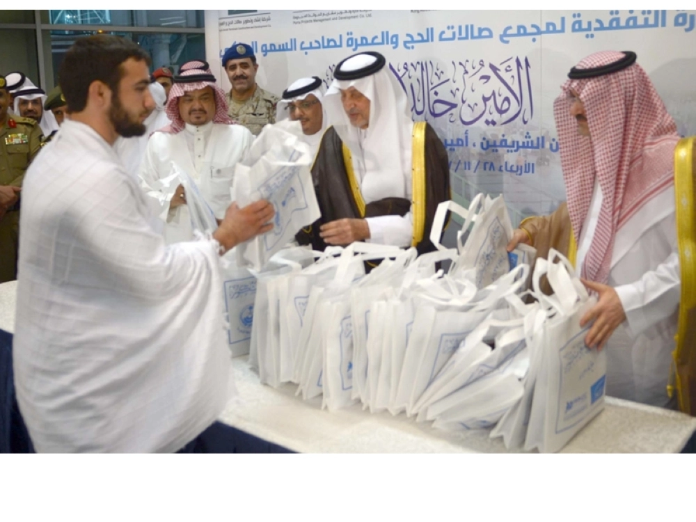 خالد الفيصل مقدما الهدايا لعدد من الحجاج لدى وصولهم المطار