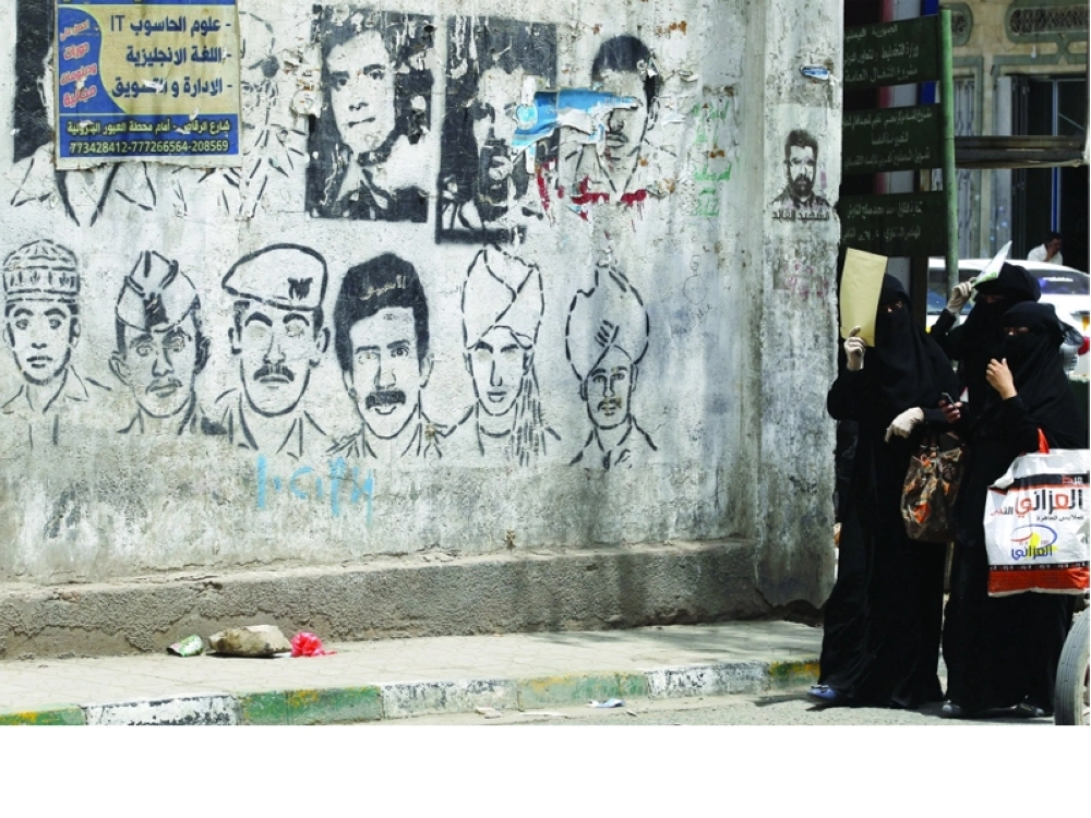 يمنيات يسرن بجوار رسم جرافيتي على جدار في صنعاء بمناسبة اليوم العالمي لضحايا الاختفاء القسري                                                                    (إ ب أ)