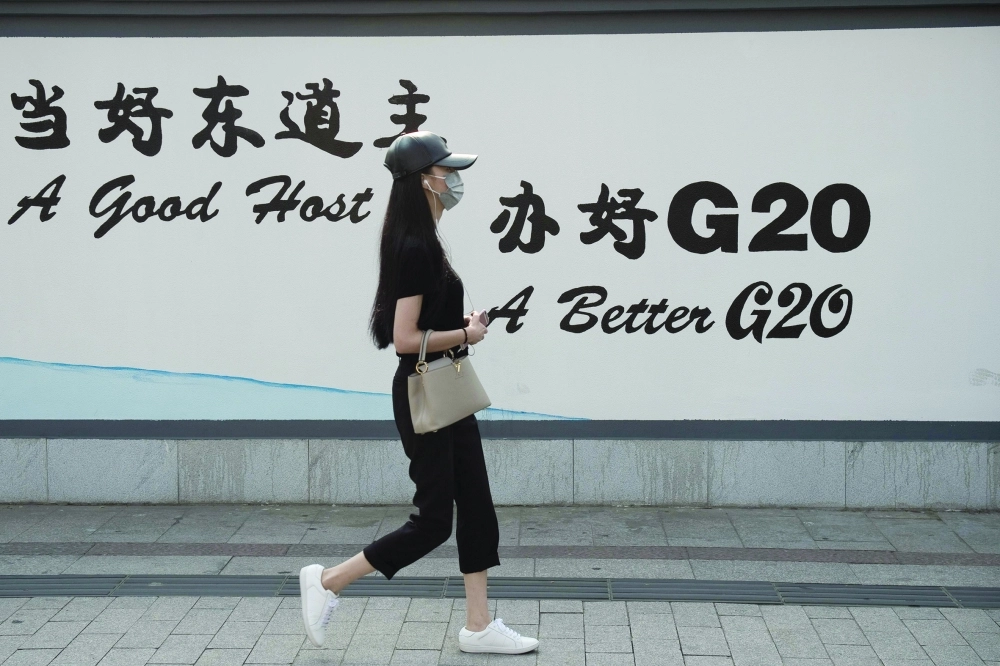 سيدة تمر بجانب إحدى اللوحات الإعلانية للقمة              (أ ف ب)