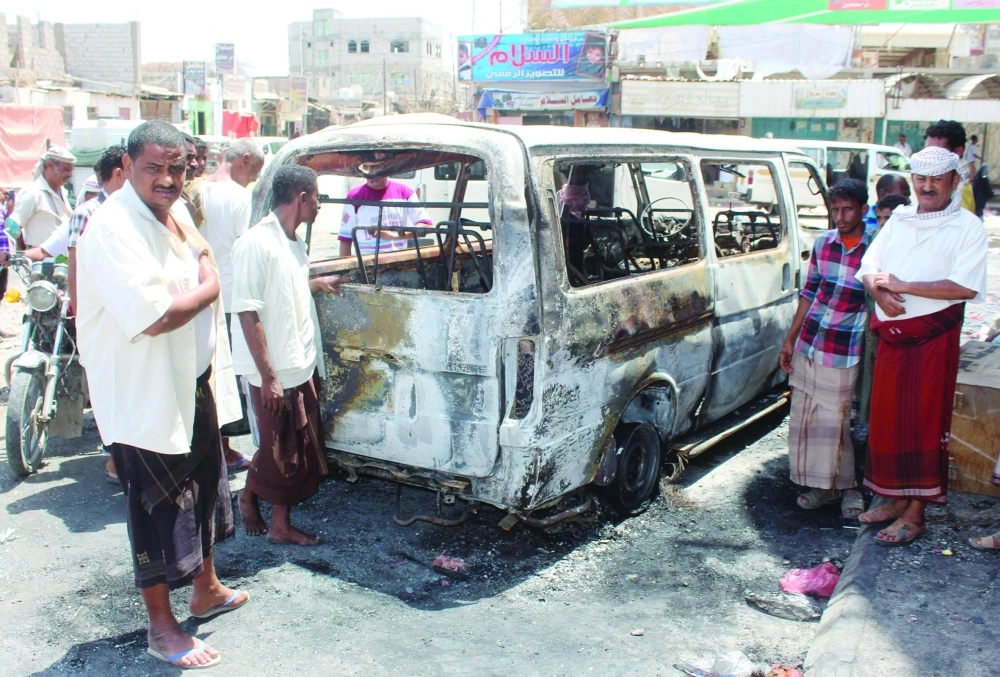 يمنيون حول حافلة صغيرة تحطمت بانفجار عبوة في حوطة لحج أمس              (أ ف ب)