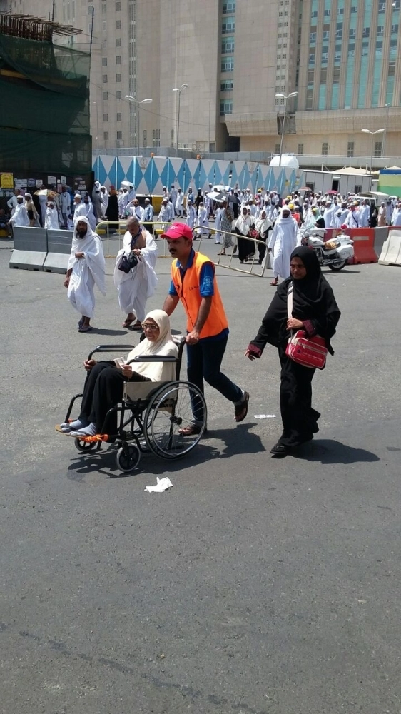 أحد أعضاء الفرق التطوعية الهندية يدفع عربة مسنة (مكة)