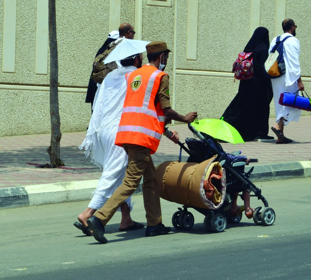 رجل أمن يساعد حاجا بدفع عربة طفله                  (عبدالمحسن دومان)  