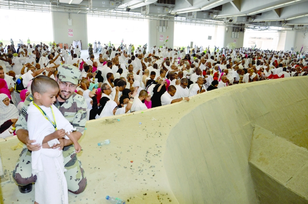 رجل أمن يساعد طفلا على رمي الجمرات أمس                        (عبد المحسن دومان)