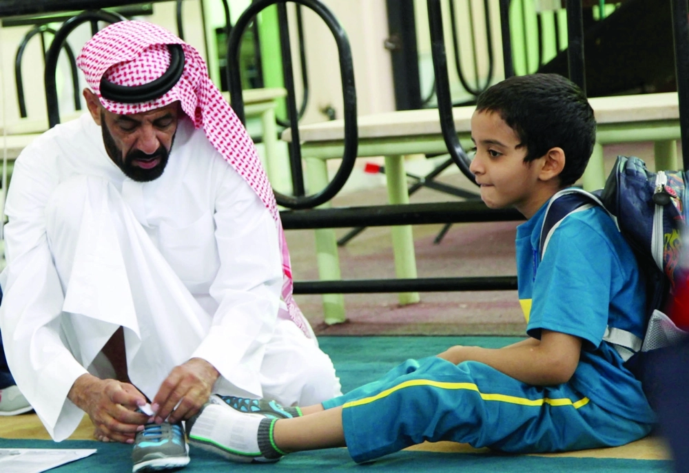 أب يساعد ابنه في ربط حذائه أمس (محمد مشهور)