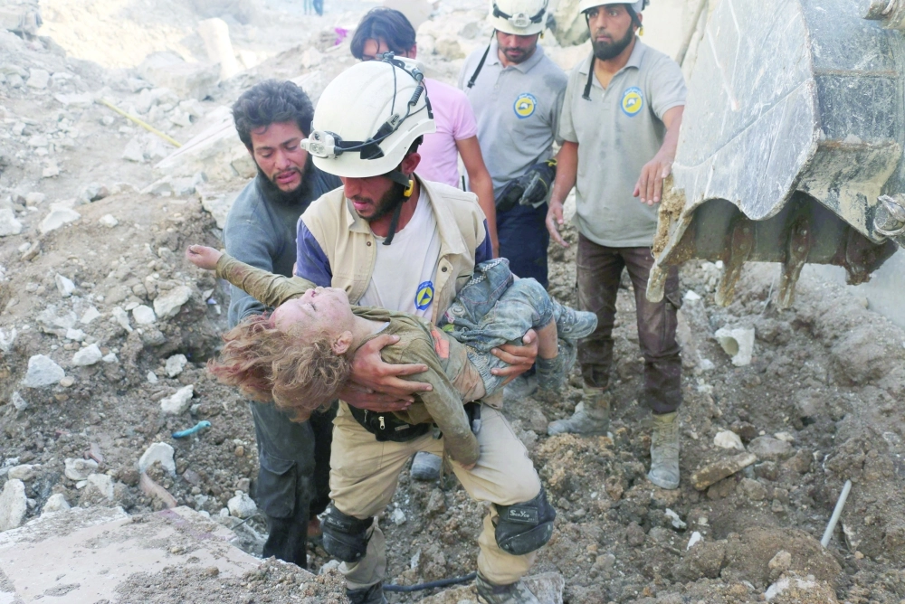 مسعف يحمل جثة طفل انتشل من تحت الأنقاض بعد غارة للنظام على حلب أمس                                                   (أ ف ب)