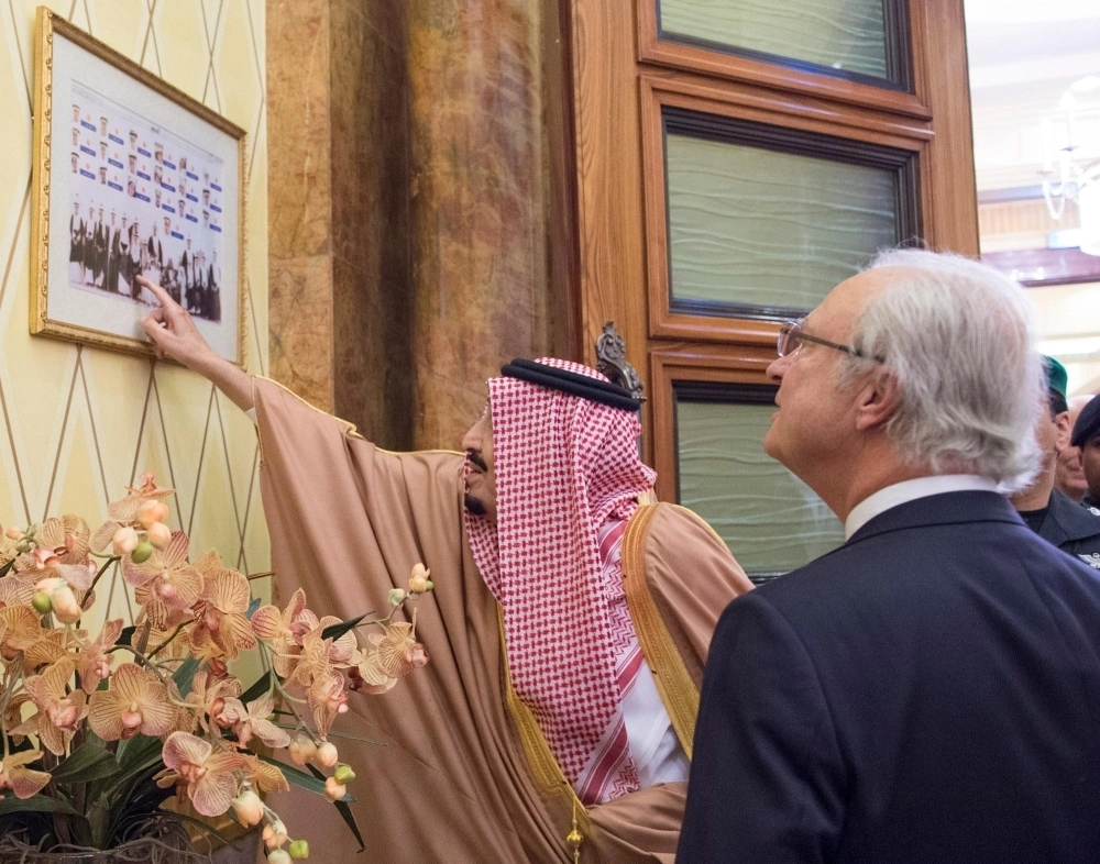 الملك سلمان يشير إلى إحدى الصور داخل قصره