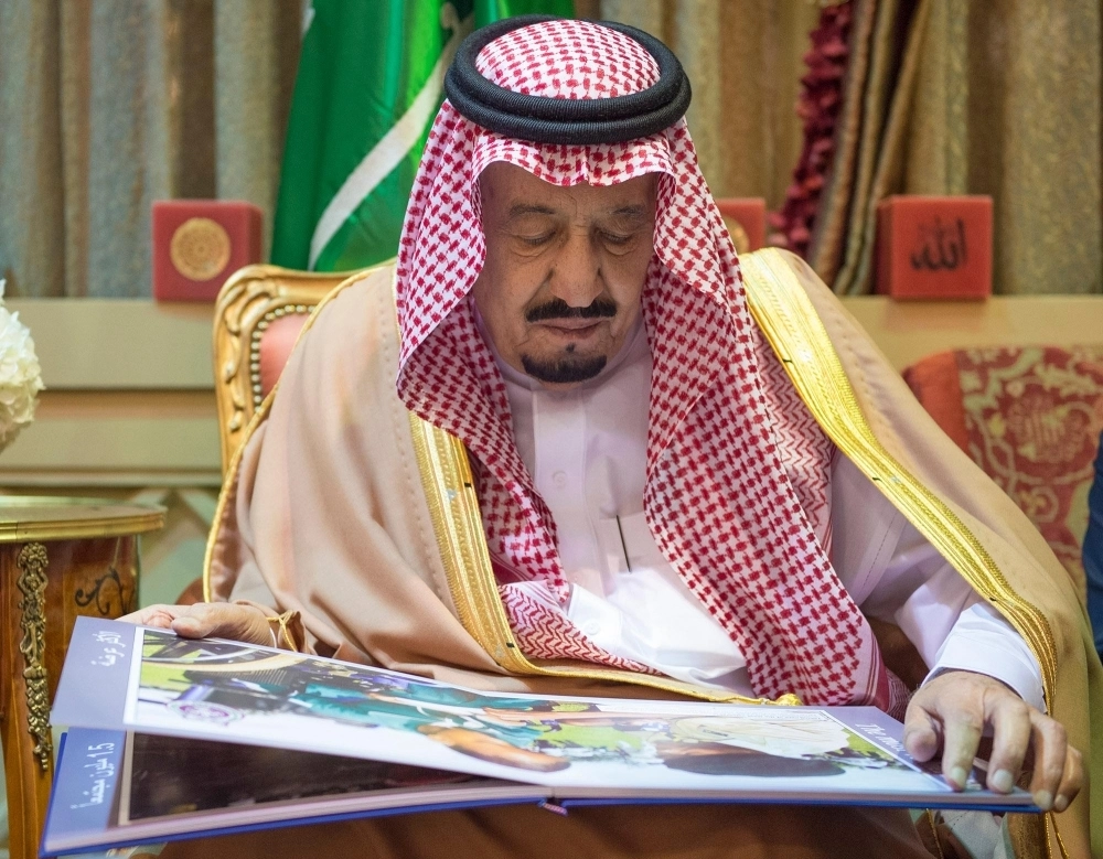الملك سلمان مطلعا على إحدى المطبوعات 